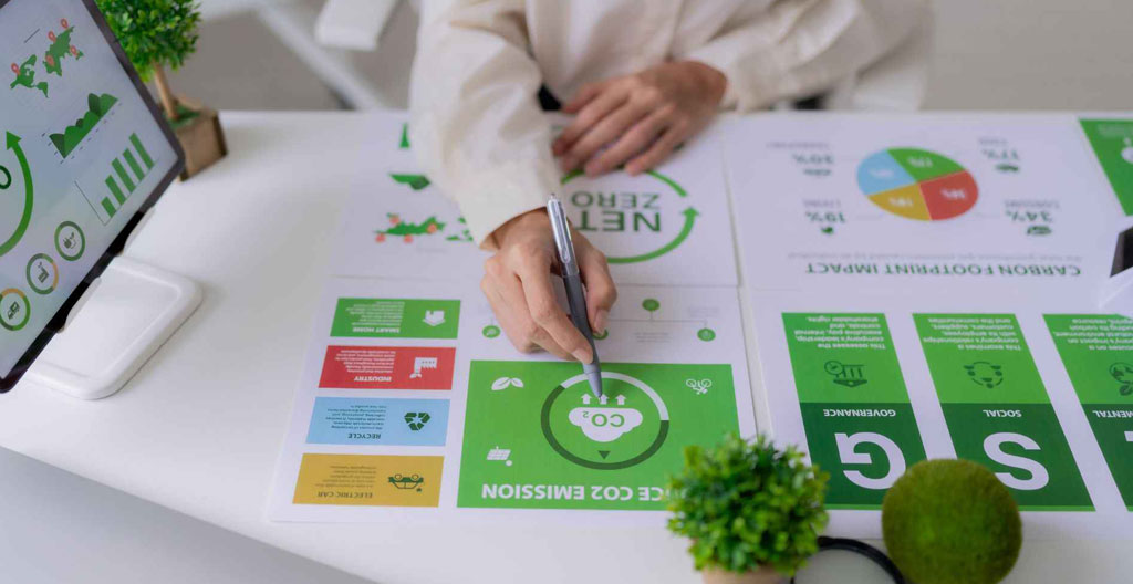 Mains tenant un rapport papier avec graphiques sur un bureau parsemé de documents et stylos